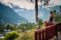 Una mujer sentada en una barandilla mirando un valle. en Vinje Camping, en Geiranger