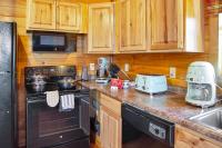eine Küche mit Holzschränken und einem Backofen mit schwarzem Kochfeld in der Unterkunft Cabin In The Smokeys in Gatlinburg