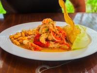 Un plato de comida con camarones y verduras en una mesa. en Casa Hotel Mamaluna, en Lunahuaná