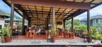 a patio with tables and chairs and people sitting at them at Khao Sok Country Resort in Khao Sok