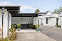 a white building with a garage with potted plants at Rolleston Motel Thames - Wenzel Motels in Thames