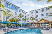 Una piscina con sillas y sombrillas frente a un hotel. en Compass by Margaritaville Hotel Naples, en Naples