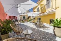 Un patio con sillas, mesas y sombrillas. en Ciraccio Apartments, en Procida