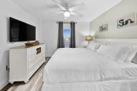 ein weißes Schlafzimmer mit einem weißen Bett und einem Flachbild-TV in der Unterkunft Beautiful Updated Pelican Beach Unit!!! in Destin
