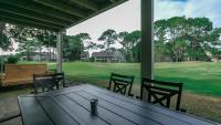 einen Tisch und Stühle auf einer Veranda mit Blick auf ein Feld in der Unterkunft Cozy renovated ground floor unit - Golf Villa - on the Golf Course in Destin