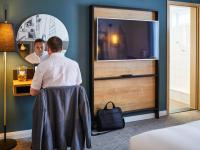 a man standing in front of a mirror in a hotel room at Mercure Cardiff North Hotel in Cardiff