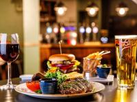 a plate of food with a hamburger and a glass of wine at Mercure Cardiff North Hotel in Cardiff