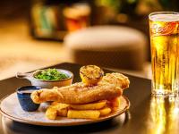 a plate of food with fish and fries and a glass of beer at Mercure Cardiff North Hotel in Cardiff