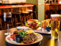 a table with a burger and a glass of beer at Mercure Cardiff North Hotel in Cardiff