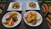three plates of food on a table with plates of food at The Landing Hotel And Restaurant in Moyogalpa