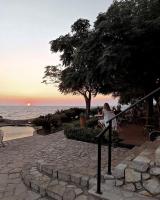 Una mujer sentada en una barandilla mirando la puesta de sol en Hotel R, en Utjeha