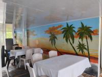 uma sala de jantar com mesas e cadeiras e um mural de palmeiras em HOSTAL LAMAR BARU dónde Gertrudis em Playa Blanca