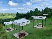 eine Gruppe von Tischen und Sonnenschirmen auf einem Feld in der Unterkunft Alpine Villas Greens Staycation at Crosswinds Tagaytay in Tagaytay