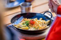 una persona que sostiene una bandeja de comida sobre una mesa en Hotel Restaurant Berghaus Malbun Buchserberg, en Buchs