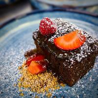 une part de gâteau au chocolat avec une fraise sur une assiette bleue dans l'établissement The Enniskillen Hotel and Motel, à Enniskillen