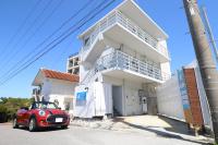 un coche rojo estacionado frente a una casa blanca en パークサイドモリ, en Motobu