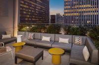eine Dachterrasse mit einem Sofa sowie Tischen und Gebäuden in der Unterkunft Hampton Inn by Hilton New York Times Square in New York