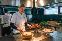 JevnakerにあるThorbjørnrud Hotellのキッチンに立って料理の準備をしている女性