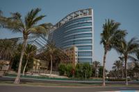 Un edificio alto con palmeras delante. en Seafront Luxury Suites Jeddah Corniche, en Yeda