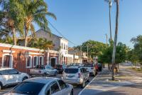 a city street with parked cars and palm trees at Pousada Boulevard in Cabo Frio