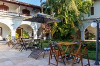 an outdoor patio with tables and chairs and an umbrella at Pousada Boulevard in Cabo Frio