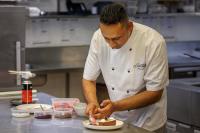 a chef preparing a plate of food in a kitchen at JetPark Auckland Airport Hotel in Auckland