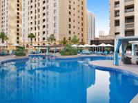 ein großer Pool in einer Stadt mit Gebäuden in der Unterkunft Mövenpick Hotel Jumeirah Beach in Dubai