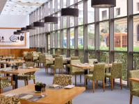 ein Restaurant mit Tischen und Stühlen und großen Fenstern in der Unterkunft Mövenpick Hotel Jumeirah Beach in Dubai