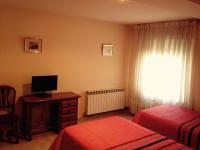 1 dormitorio con 2 camas, TV y ventana en Hostal Nicolás, en Medinaceli