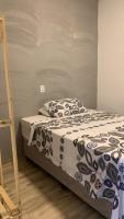a bed with a black and white comforter and a ladder at Pousada QUERÊNCIA FRANCÊS in Marechal Deodoro