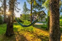 a hammock hanging between two trees in front of a house at Malachit Karpacz SPA Hotel in Karpacz