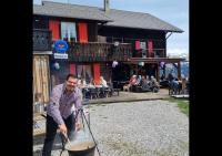 a man holding a large pot in front of a building at Bergpension Battagliahütte in Malix
