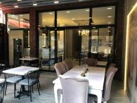 Un restaurante con mesas y sillas blancas y ventanas. en Rinascente, en Edirne