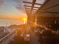 un grupo de personas sentadas en un restaurante viendo la puesta de sol en Boutique Hotel Jardim Do Mar, en Jardim do Mar