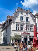 un edificio blanco con gente sentada fuera de él en Hotel Albers, en Recklinghausen