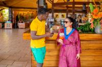 Un hombre y una mujer de pie junto a un bar. en Royal Horizon Baobab, en Somone