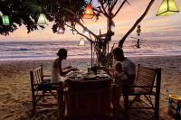 a family sitting at a table on the beach at Breizh Cape Beach Bungalows in Ko Lanta