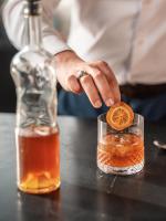 a man is putting a orange slice in a drink at Hotel OFF Paris Seine in Paris