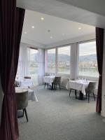 un restaurant avec des tables et des chaises blanches et de grandes fenêtres dans l'établissement Logis Hôtel Le Bellevue, à Les Roches-de-Condrieu