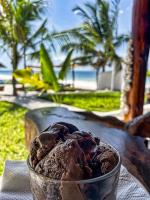 a bowl of chocolate ice cream on a table near the beach at AVO Boutique Hotel in Dikoni