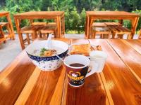 มนต์จันทรา เฮ้าส์ في Khlong Lan: كوبان من القهوة ووعاء من الطعام على طاولة خشبية