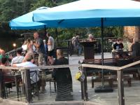 een groep mensen die aan tafel zitten onder een blauwe paraplu bij Maison Bonheur Resort Bousset in Chiddes