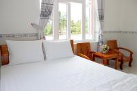 a bedroom with a white bed with two chairs and a window at Hung Phuc Mui Ne Hotel in Mui Ne