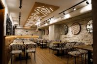 a restaurant with tables and chairs and a brick wall at Hotel Kalemi 2 in Gjirokastër