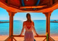 Una mujer con un vestido blanco mirando hacia el océano en Davinci Beach Resort, en Hurghada