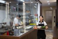 a woman holding a tray of food in a kitchen at Khách sạn Hoàng Yến in Lao Cai