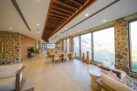 uma sala de jantar com mesas e cadeiras e janelas grandes em Najd Al Meqsar, By Sharjah Collection - Adults Only em Khor Fakkan