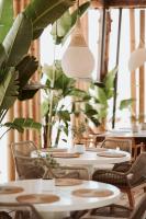 uma fila de mesas e cadeiras numa sala com plantas em Palladium Beach Hotel- Luxury Leading Hotels, Private Beach Included em Dhërmi