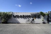 Una bicicleta estacionada frente a un muro con un grafiti en La Cordata Accommodation - Woodhouse Bike Hotel, en Cinisello Balsamo
