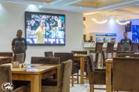 two men standing in a dining room with tables at Hadmof Hotel and Suites in Ikeja